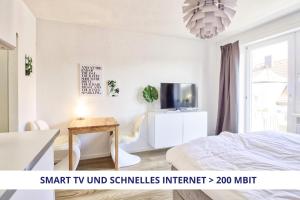 a bedroom with a bed and a table and a tv at Apt Wahnfried No2 - sehr zentrales, ruhiges Cityapartment mit Balkon, Küche, Duschbad & Parkplatz in Bayreuth