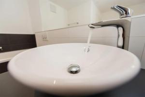 a white sink with water coming out of a faucet at Moderne Wohnung Jungtal in Grächen +16 photos