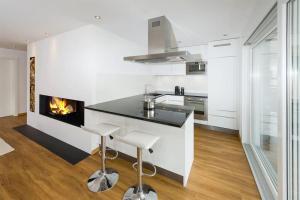 a kitchen with a fireplace and a counter with stools at Moderne Wohnung Jungtal in Grächen