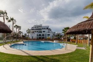 a swimming pool with a large building in the background at RentitSpain - Playa Granada - Apartamento Aguacate Golf y Costa in Motril