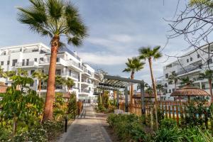 a pathway with palm trees in front of a building at RentitSpain - Playa Granada - Apartamento Aguacate Golf y Costa in Motril