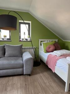 um quarto com paredes verdes, uma cama e um sofá em Apartament Nawojowski em Nowy Sącz