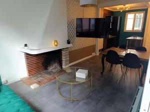 sala de estar con chimenea, mesa y TV en Au logis Corneille, en Rouen