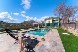 a swimming pool with two chairs and a house at Serenity Villas in Kolymbia
