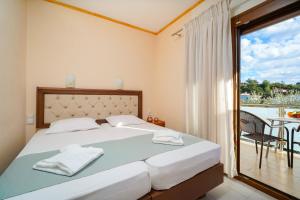 a bedroom with a bed with a view of a balcony at Lampiris Beach Front Apartments in Potos