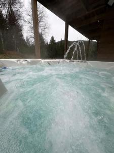 a hot tub with a water fountain in a backyard at Chalet de l'ancienne école, Jacuzzi privé in Gérardmer