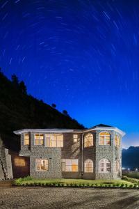 une grande maison en pierre avec un ciel étoilé la nuit dans l'établissement Charmed Chateau, à Shimla