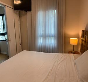 sypialnia z dużym białym łóżkiem i lampką w obiekcie Charmoso Flat em Pinheiros w São Paulo