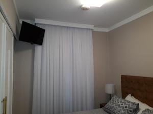 sypialnia z łóżkiem z zasłoną i telewizorem w obiekcie Charmoso Flat em Pinheiros w São Paulo