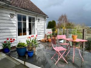 um pátio com uma mesa rosa, cadeiras e plantas em Cobblers Lodge em Lyme Regis