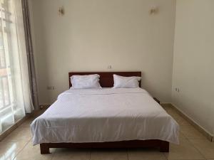 Rubavu的住宿－NINHO APPARTEMENT，卧室配有一张带白色床单和枕头的大床。