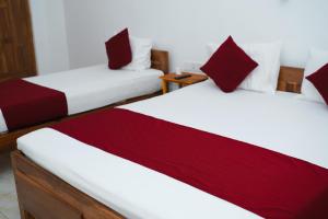 two beds in a room with red and white at Hotel Theevanni Inn in Trincomalee