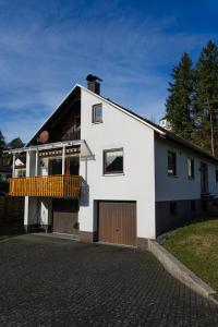 a white house with a balcony and a garage at Ferienwohnung Am Rhaunelbach in Rhaunen +19 photos