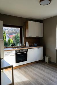 una cocina con armarios blancos y una ventana en Ferienwohnung Am Rhaunelbach, en Rhaunen