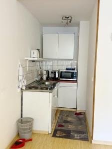 a small kitchen with white cabinets and a microwave at 2 Zimmer Appartement mit Pool im Haus in Schluchsee