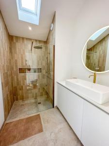 uma casa de banho com um lavatório e um chuveiro com um espelho. em L’Abri-Cotier - Maison rénovée em Dinard