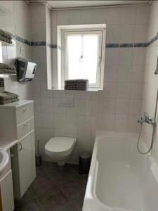 ein Bad mit einer Badewanne, einem WC und einem Fenster in der Unterkunft Monteur- und Ferienwohnung 1 - Haus Weitblick Schonungen in Schonungen