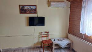 a room with a table and a chair and a tv at Napsugár Panzió in Vác