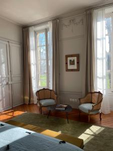 uma sala de estar com 2 cadeiras, uma mesa e janelas em Le Mûrier de Bayeux em Bayeux