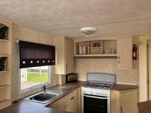 eine kleine Küche mit Herd und Spüle in der Unterkunft Caravan Sleeps 4 with Free Parking in Burnham on Sea + 6 Fotos