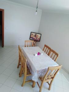 Appartement agadir centre في أغادير: طاولة طعام مع طاولة بيضاء من قماش وكراسي