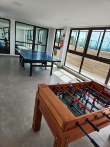 a ping pong table in a room with windows at Apartamento - Centro Porto de Galinhas in Escada +8 photos