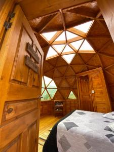 a room with a bed in a wooden cabin at Glamping domo el colibrí in Choachí