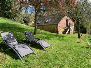 due sedie sedute nell'erba di fronte a un fienile di Gite Le Refuge a Vimoutiers