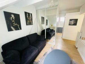 a living room with a black couch and a mirror at Studio Parc des Princes - Porte dauphine - 2 Pers in Boulogne-Billancourt