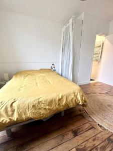 - une chambre avec un lit jaune et du parquet dans l'établissement Appartement Pantin, à Pantin