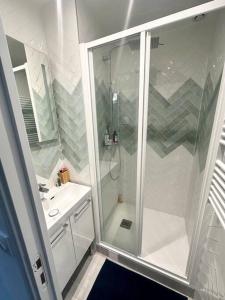 La salle de bains blanche est pourvue d'une douche et d'un lavabo. dans l'établissement Appartement Pantin, à Pantin