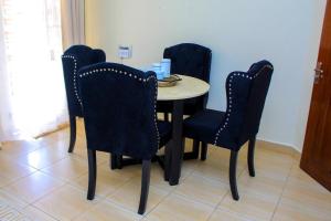 a dining room table with four chairs and a table with aermott at POPPI HOUSE 3 bedroom in Kampala