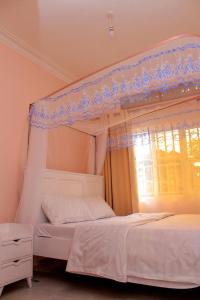 a bedroom with a canopy bed and a window at POPPI HOUSE 3 bedroom in Kampala