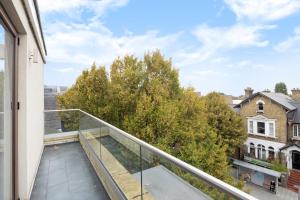 balcón con vistas a los árboles y edificios en Charming One-Bedroom Retreat in Kingston KT2, London en Kingston upon Thames