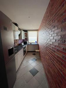 a kitchen with a red brick wall next to a counter at Apartament pod chmurami 2 pokoje in Opole