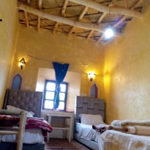 Cette chambre comprend 2 lits et une fenêtre. dans l'établissement Dar adiafa dar asalam, à Aït Ben Haddou