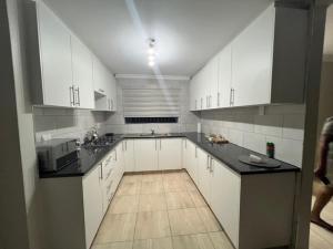 a large kitchen with white cabinets and black counter tops at Tintswalo Elegant Apartments in Giyani