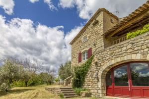 a stone building with a red door on a field at Mas Chantequinson in Les Assions