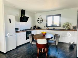eine Küche mit einem Tisch und Stühlen sowie einem Kühlschrank in der Unterkunft Maison de vacances in Tonnay-Charente