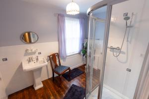 a bathroom with a shower and a sink and a chair at Big Sky Guest House- ROOM ONLY in Whitby