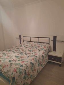 - un lit avec une couette à fleurs et une table de nuit dans l'établissement Malena, à Pogradec