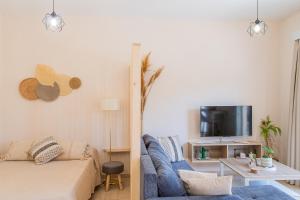 a living room with a blue couch and a tv at Casa Calida - 500m to Kos Town in Kaká Pinári