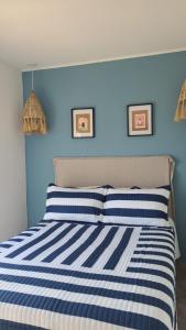 Dormitorio azul con cama de rayas azules y blancas en Departamento Boutique del mar en Monte Hermoso