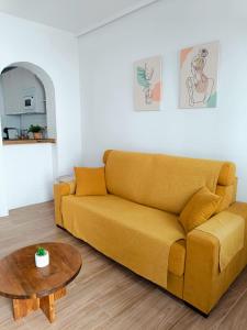 sala de estar con sofá amarillo y mesa en Casita El Lagar, en Estepona