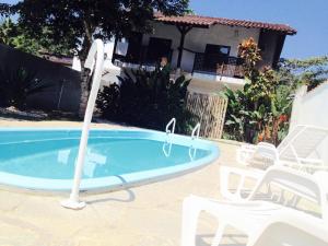 uma piscina com um gazebo e cadeiras ao lado de uma casa em Itamambuca Casa de Praia em Ubatuba