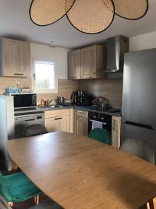 eine Küche mit einem Holztisch mit Stühlen und einem Kühlschrank in der Unterkunft Maison Guerande La Baule in Guérande