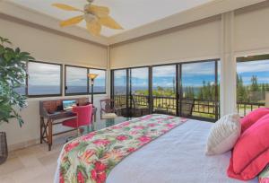 a bedroom with a bed and a balcony with windows at 622 Kapalua Ridge Villa in Kahana