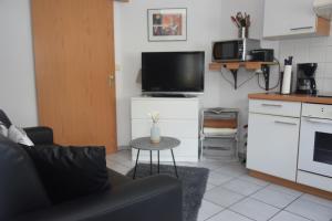een woonkamer met een bank en een tv en een keuken bij Haus Luzia in Sankt Aldegund