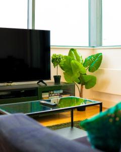 ein Wohnzimmer mit einem TV und einem Couchtisch aus Glas in der Unterkunft The Regency Suite - Modern 2-Bed 1-Bath Apartment in Chertsey