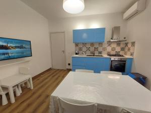 una cucina con armadi blu e tavolo e sedie bianchi di Cortile 5 Menfi a Menfi